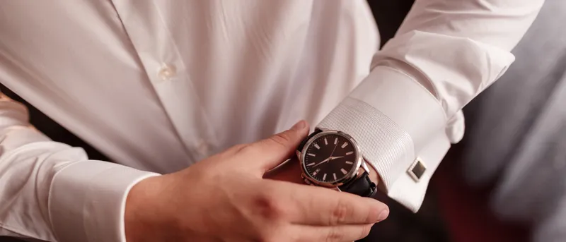 Reloj de pulsera y gemelos sobre el puño de una camisa blanca.