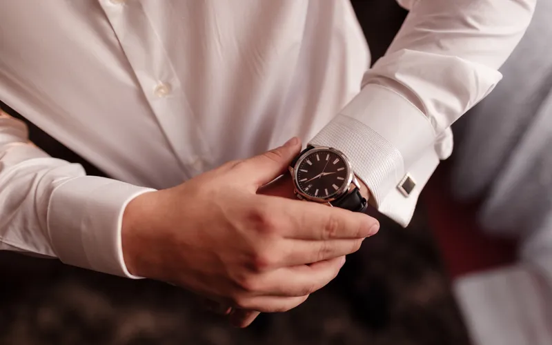 Reloj de pulsera y gemelos sobre el puño de una camisa blanca.