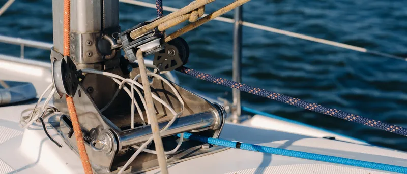 Jarcia y cabos tensados sobre la cubierta de un velero, con el mar al fondo.